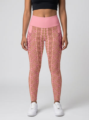 Woman wearing SunBorn N'Donso™ Pocket Leggings in Adaeze Pink, front view: high-rise solid pink waistband, side pockets and Hunter's Road print to the ankle