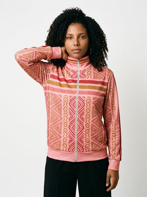 Woman wearing the SunBorn N'Donso™ Track Jacket in Eze Pink, front view: Hunter's Road print with zigzag columns, rings and nested triangles, chest stripe band, stand collar