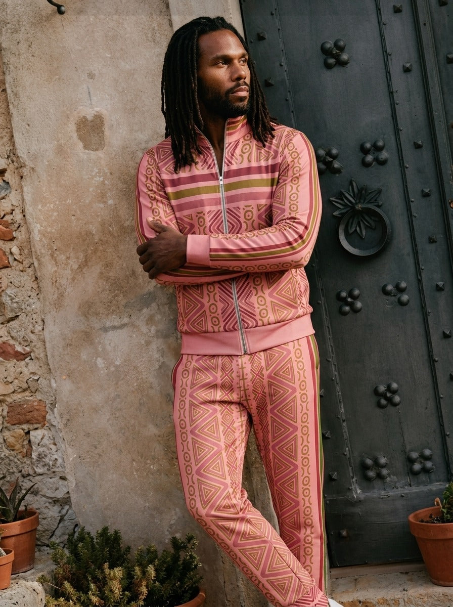 N'Donso™ Eze Pink tracksuit worn against a stone wall and iron door