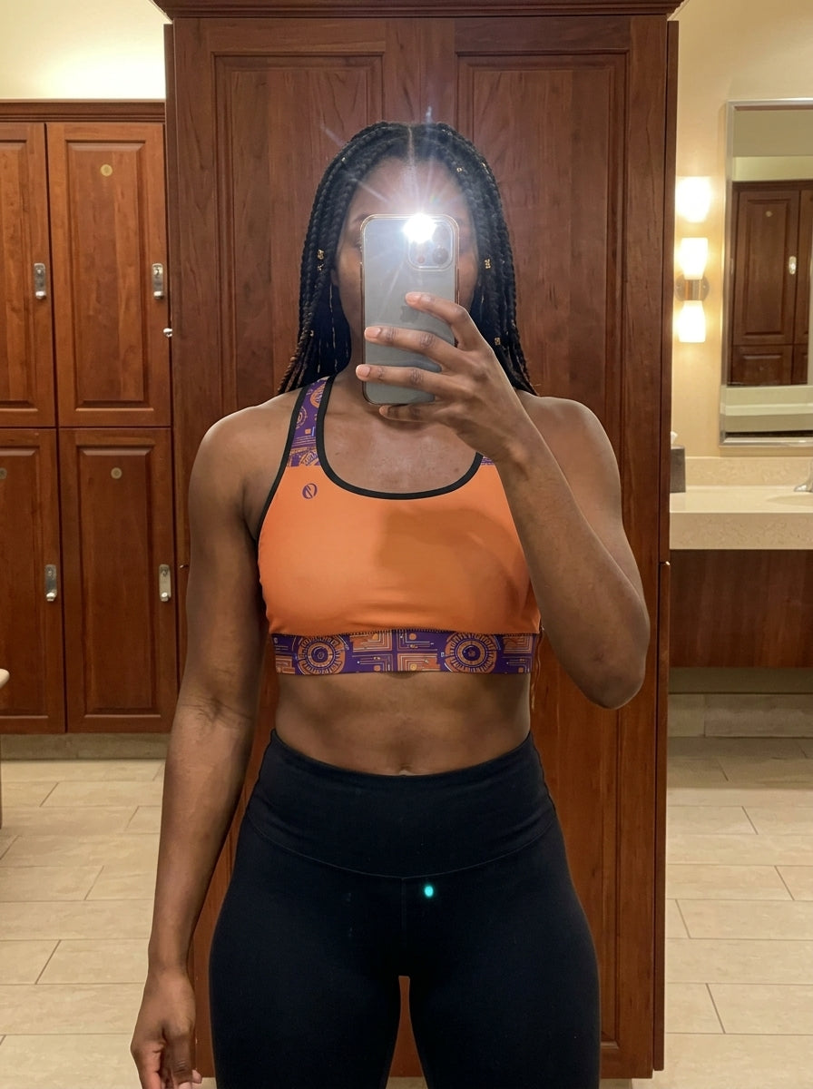 Sankofa Padded Sports Bra in the Sango Orange Kinetic Engine print, UGC mirror selfie in gym locker room — SunBorn