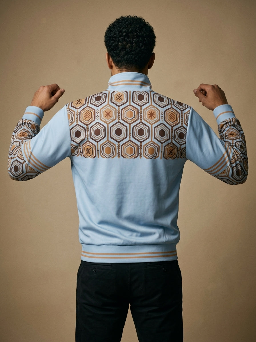 AnanseNova™ Statement Track Jacket in Igwe Blue — back view on model, hexagon print across the upper back and shoulders with striped cuffs and hem
