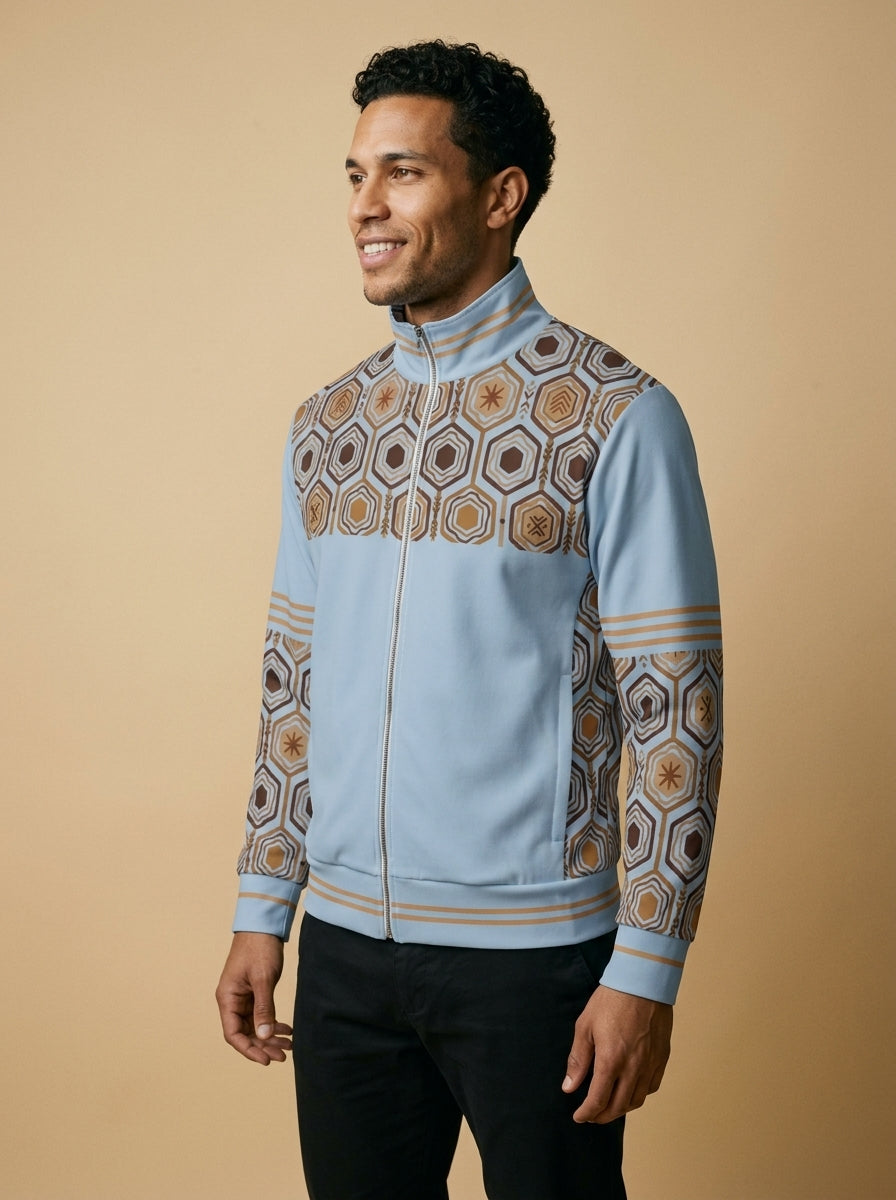 AnanseNova™ Statement Track Jacket in Igwe Blue — three-quarter left view on model, full-zip track jacket with hexagon yoke and forearm panels