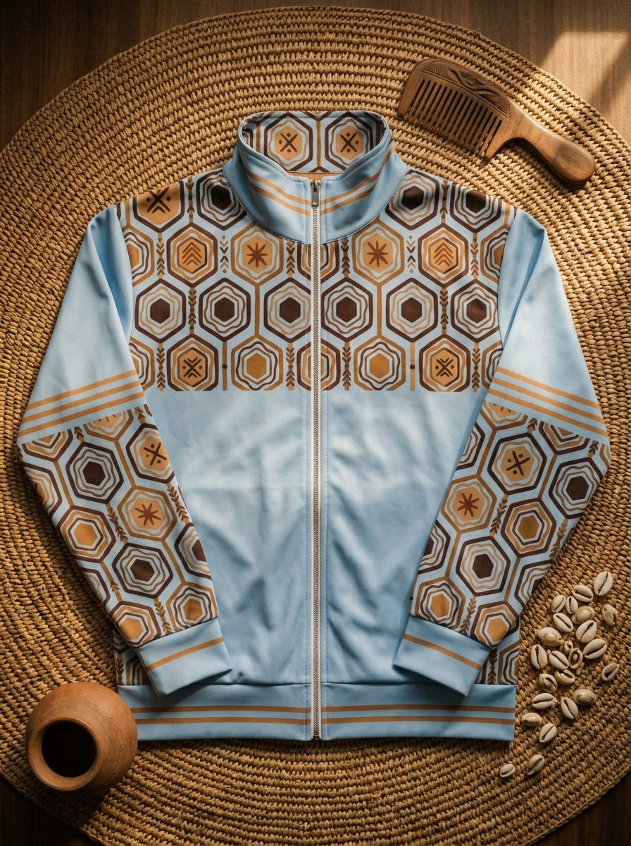 AnanseNova™ Statement Track Jacket in Igwe Blue — styled flat lay of the full-zip track jacket with hexagon print, laid on woven textiles