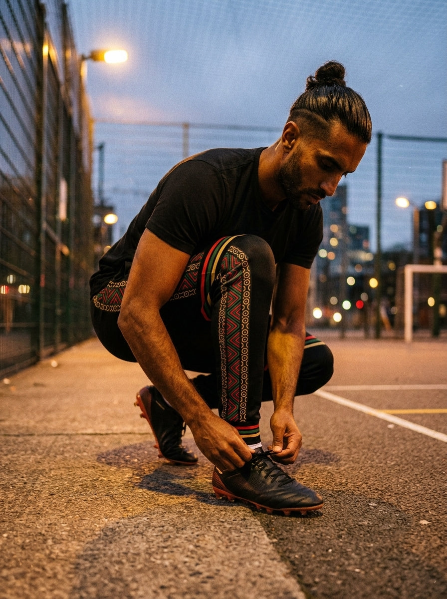 Model in the N'Donso™ Men's Joggers (Uhie Red), pitch-side warm-up lifestyle shot.