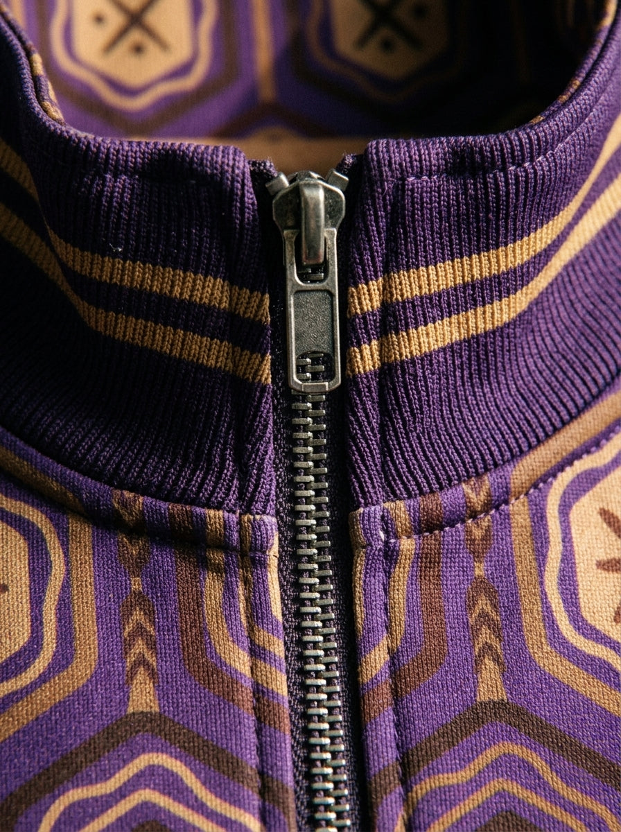 AnanseNova™ Statement Track Jacket in Ugo Purple — close-up of the zipper pull, hexagon print and triple-stripe rib cuff on AkomaDrive™ brushed fleece
