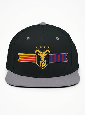 GOAT Catalan two-tone snapback in Oji Black / Ọnwa Silver, front view — the full-colour Catalan crest on the crown: gold goat, No. 10, four stars, split Senyera and blaugrana banner.