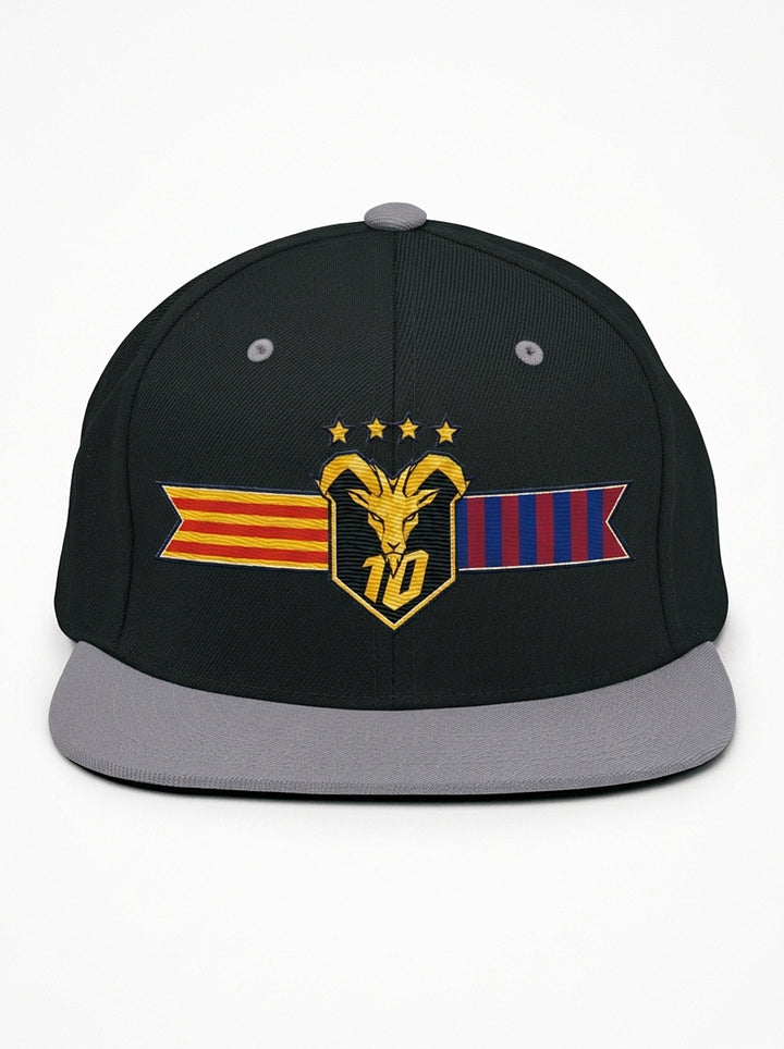 GOAT Catalan two-tone snapback in Oji Black / Ọnwa Silver, front view — the full-colour Catalan crest on the crown: gold goat, No. 10, four stars, split Senyera and blaugrana banner.