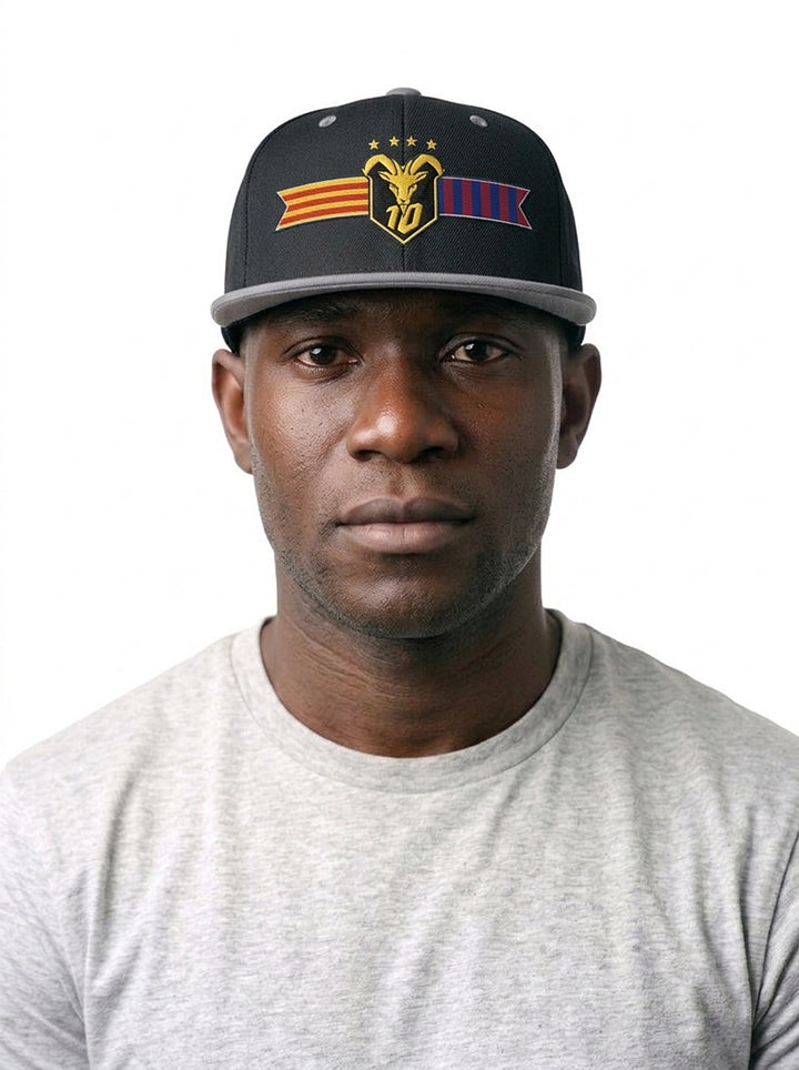 Model wearing the GOAT Catalan two-tone snapback in Oji Black / Ọnwa Silver, showing the embroidered Catalan crest on the flat-brim cap.