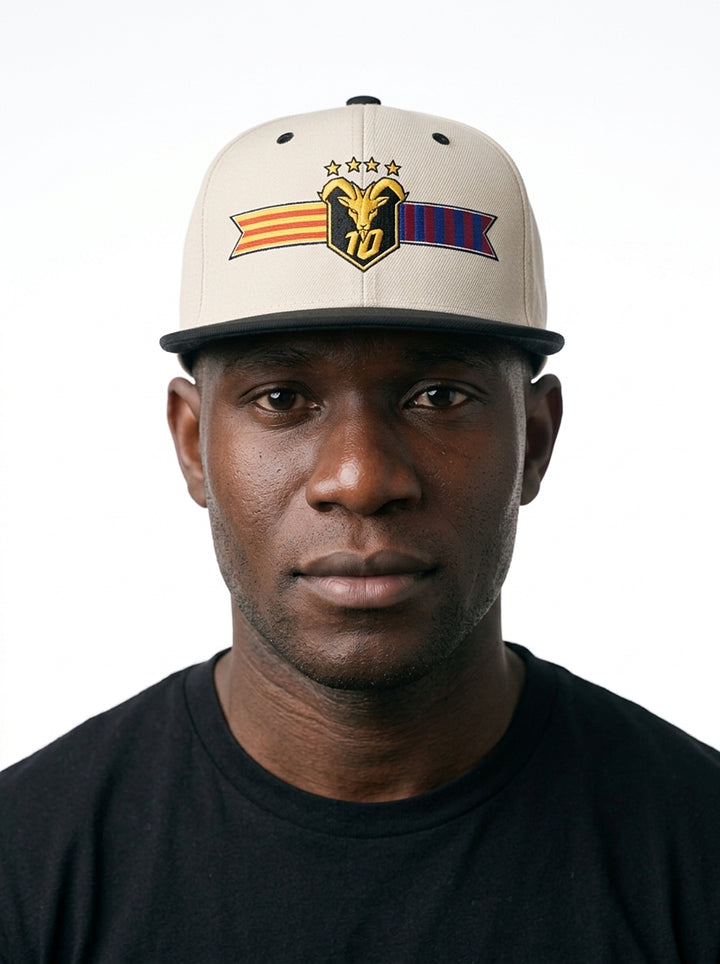 Model wearing the GOAT Catalan two-tone snapback in Ocha White / Oji Black, showing the embroidered Catalan crest on the flat-brim cap.