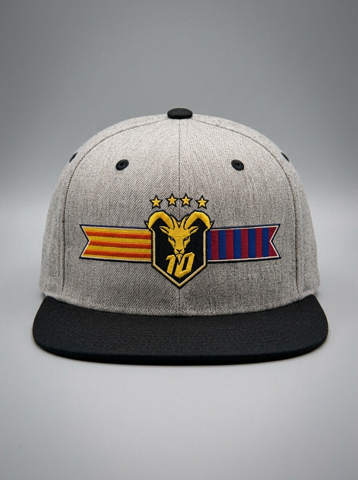 GOAT Catalan two-tone snapback in Ntụ Gray / Oji Black, front view — the full-colour Catalan crest on the crown: gold goat, No. 10, four stars, split Senyera and blaugrana banner.