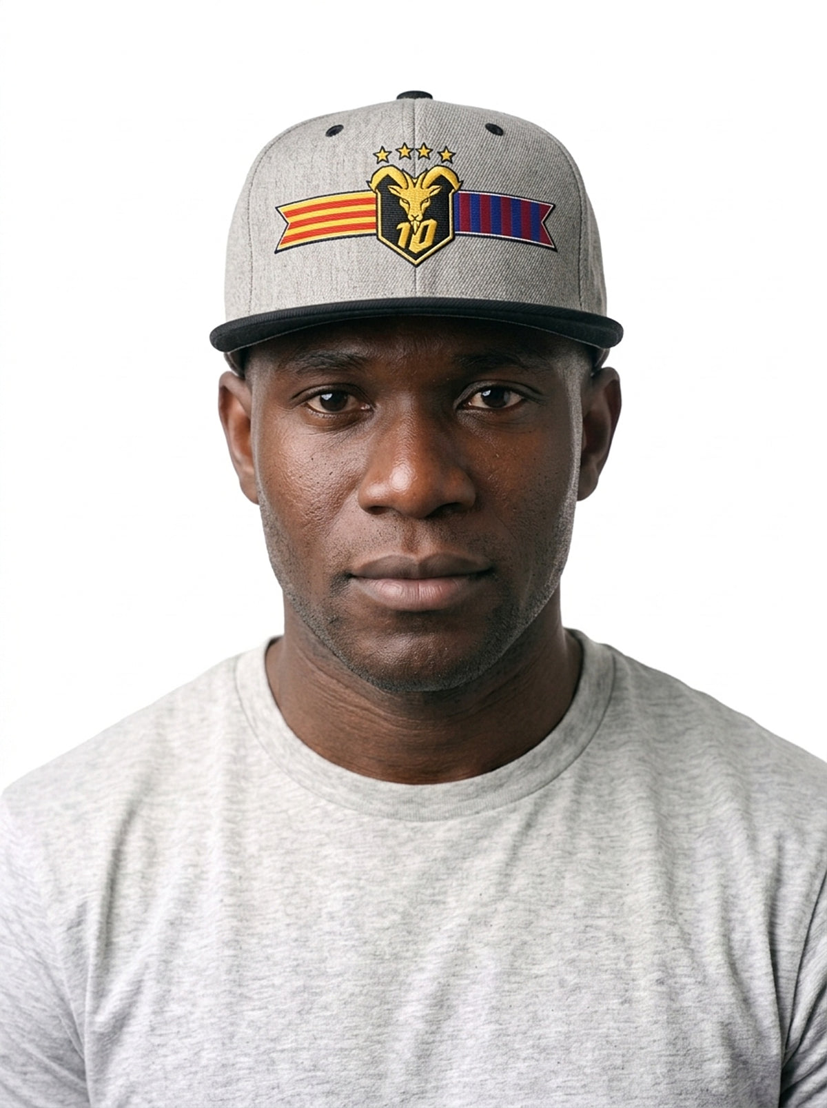 Model wearing the GOAT Catalan two-tone snapback in Ntụ Gray / Oji Black, showing the embroidered Catalan crest on the flat-brim cap.