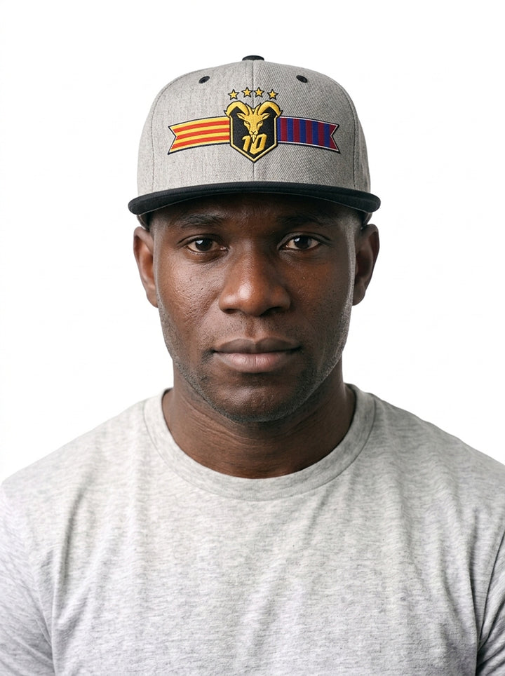 Model wearing the GOAT Catalan two-tone snapback in Ntụ Gray / Oji Black, showing the embroidered Catalan crest on the flat-brim cap.