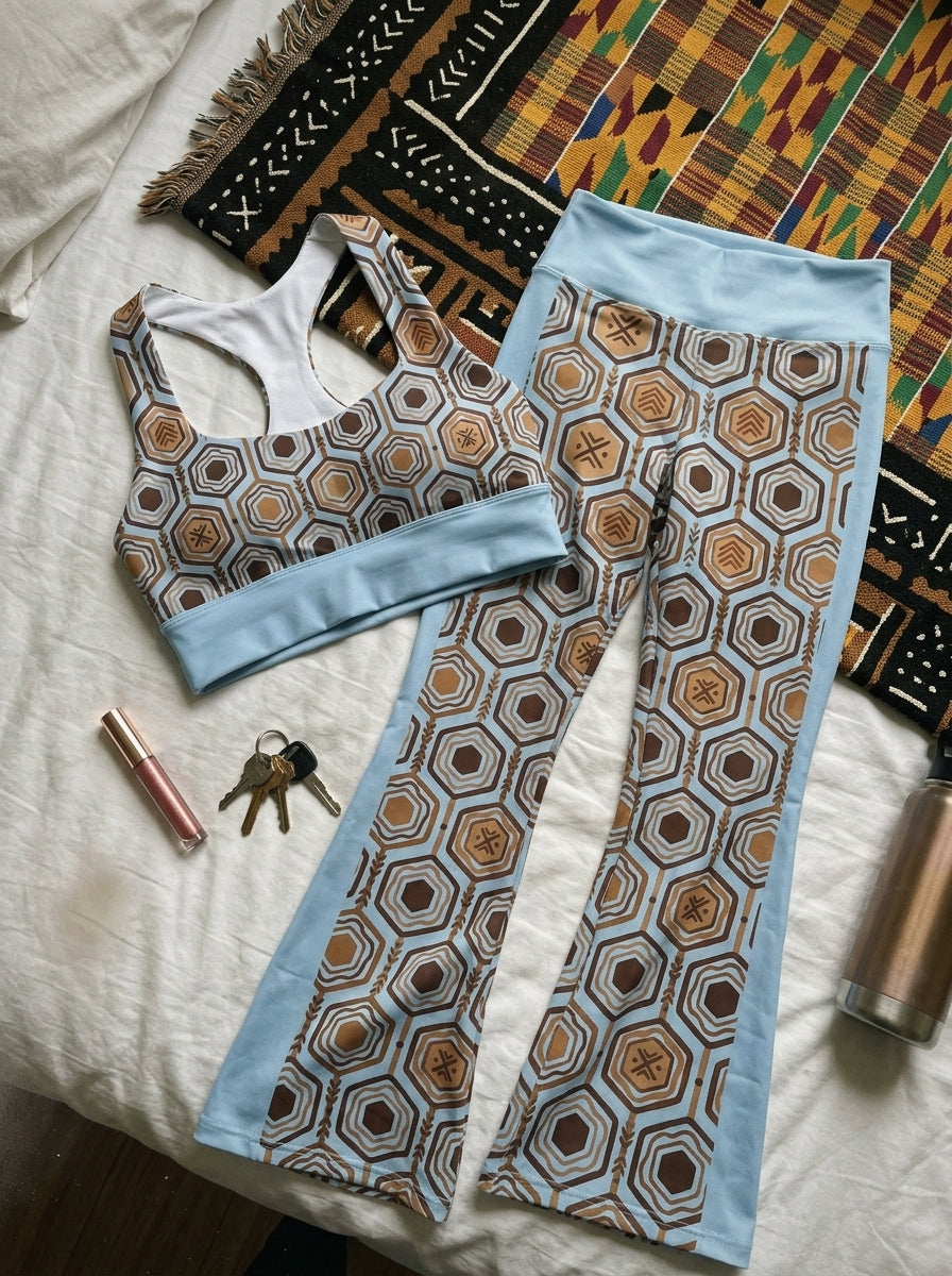 Flat-lay of the Igwe Blue AnanseNova™ Set — longline sports bra and flare leggings in hexagon print laid on the floor