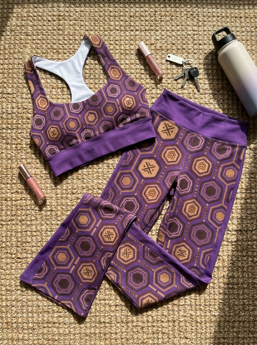 Flat-lay of the Ugo Purple AnanseNova™ Set — longline sports bra and flare leggings in hexagon print laid on the floor