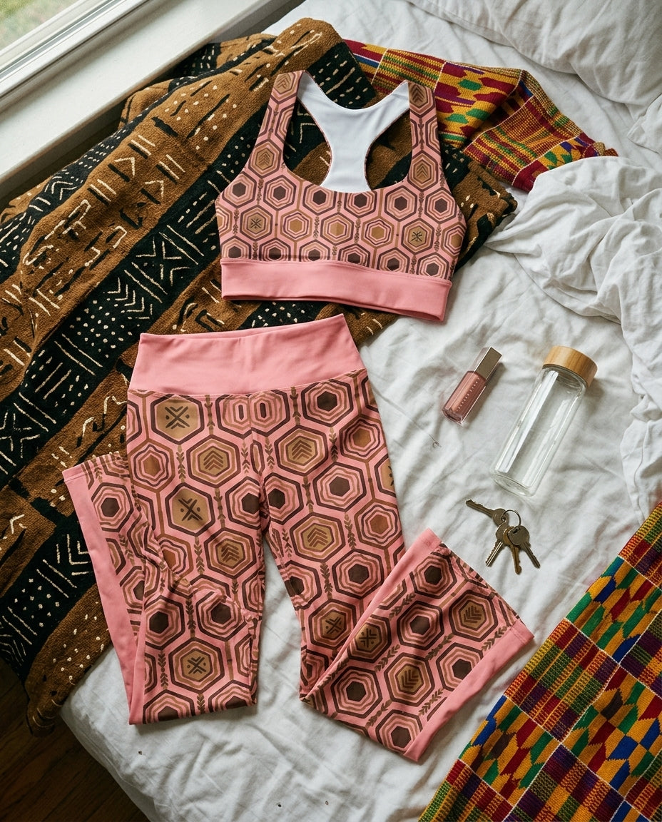 Flat-lay of the Adaeze Pink AnanseNova™ Set — longline sports bra and flare leggings in hexagon print laid on the floor
