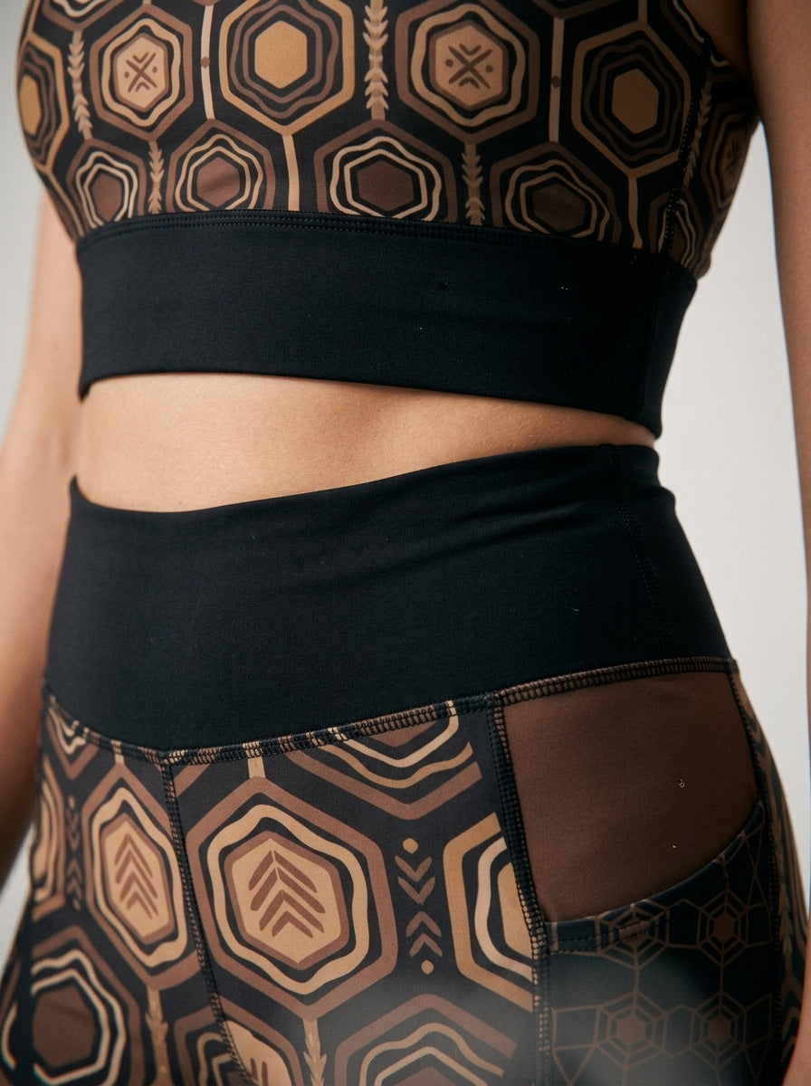 AnanseNova™ Set // Bra + Pocket Leggings in Oji Black — close-up detail of hexagon web-cell print, solid waistband, and side pocket seam on AsaseFlex™ stretch fabric