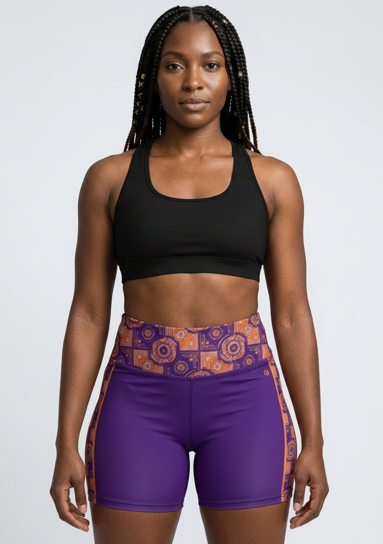 Sankofa Yoga Shorts in the purple, burnt orange and cyan Kinetic Engine print, studio front view — SunBorn